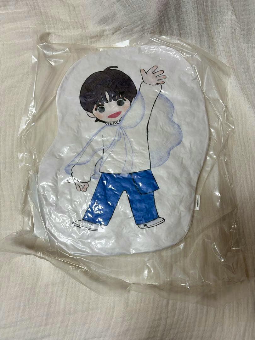 Packaged front view of the Taehyun cushion showing a cartoon figure in blue pants waving.