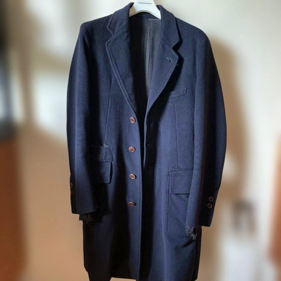Front view of the dark Chester coat hanging on a hanger, showing buttons and pockets.