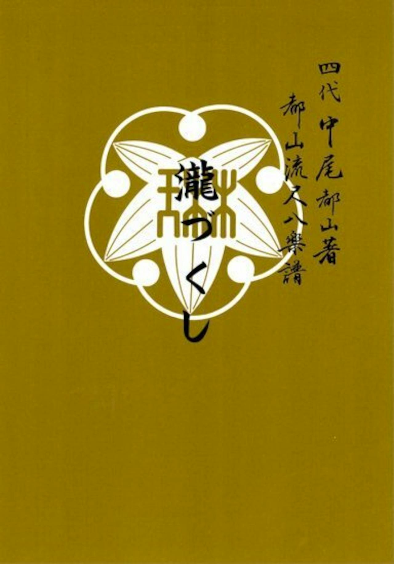 Front cover of the book showing a white decorative emblem and Japanese text on a mustard background.