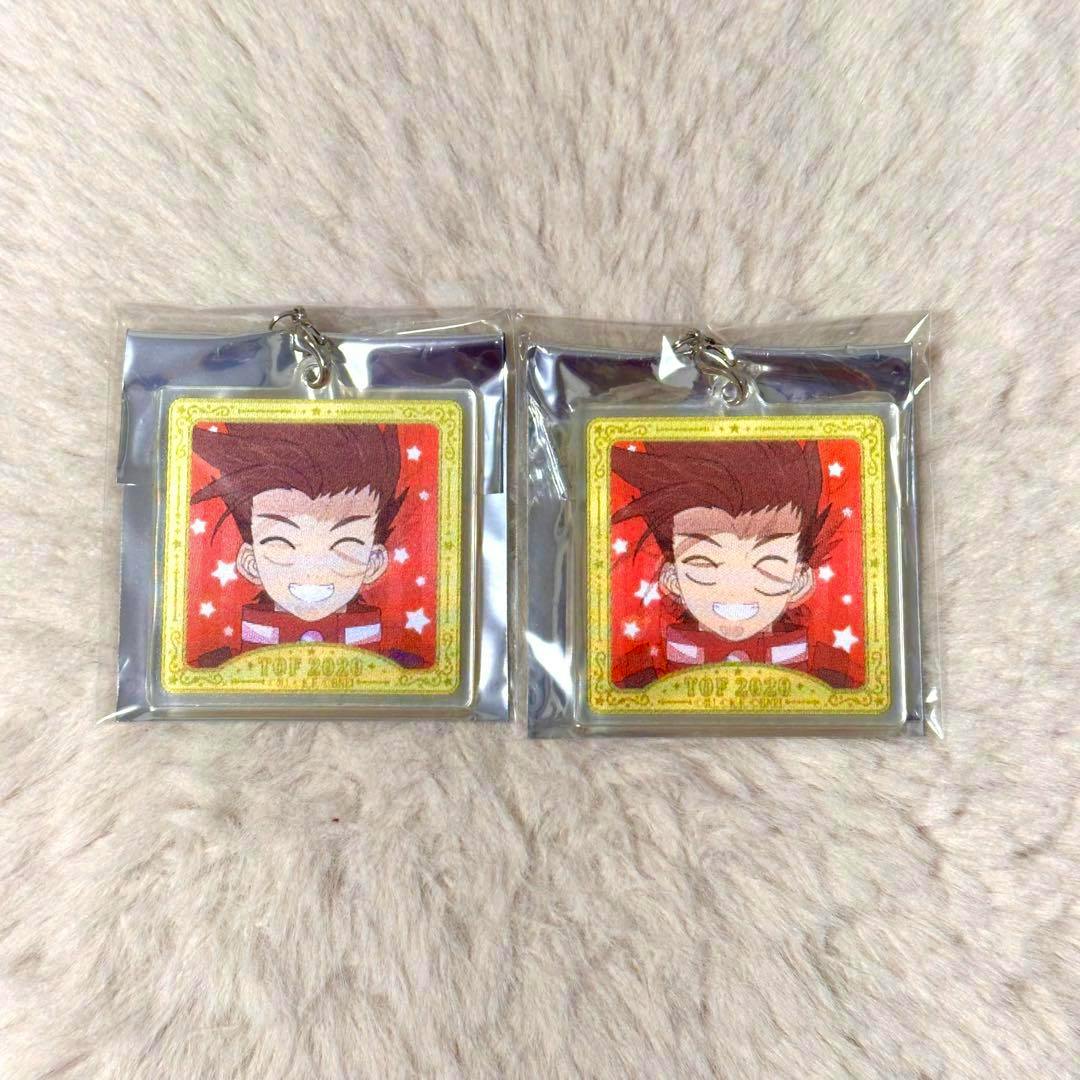 Two square acrylic keychains featuring the character Lloyd in sealed plastic packaging on a soft fabric surface.