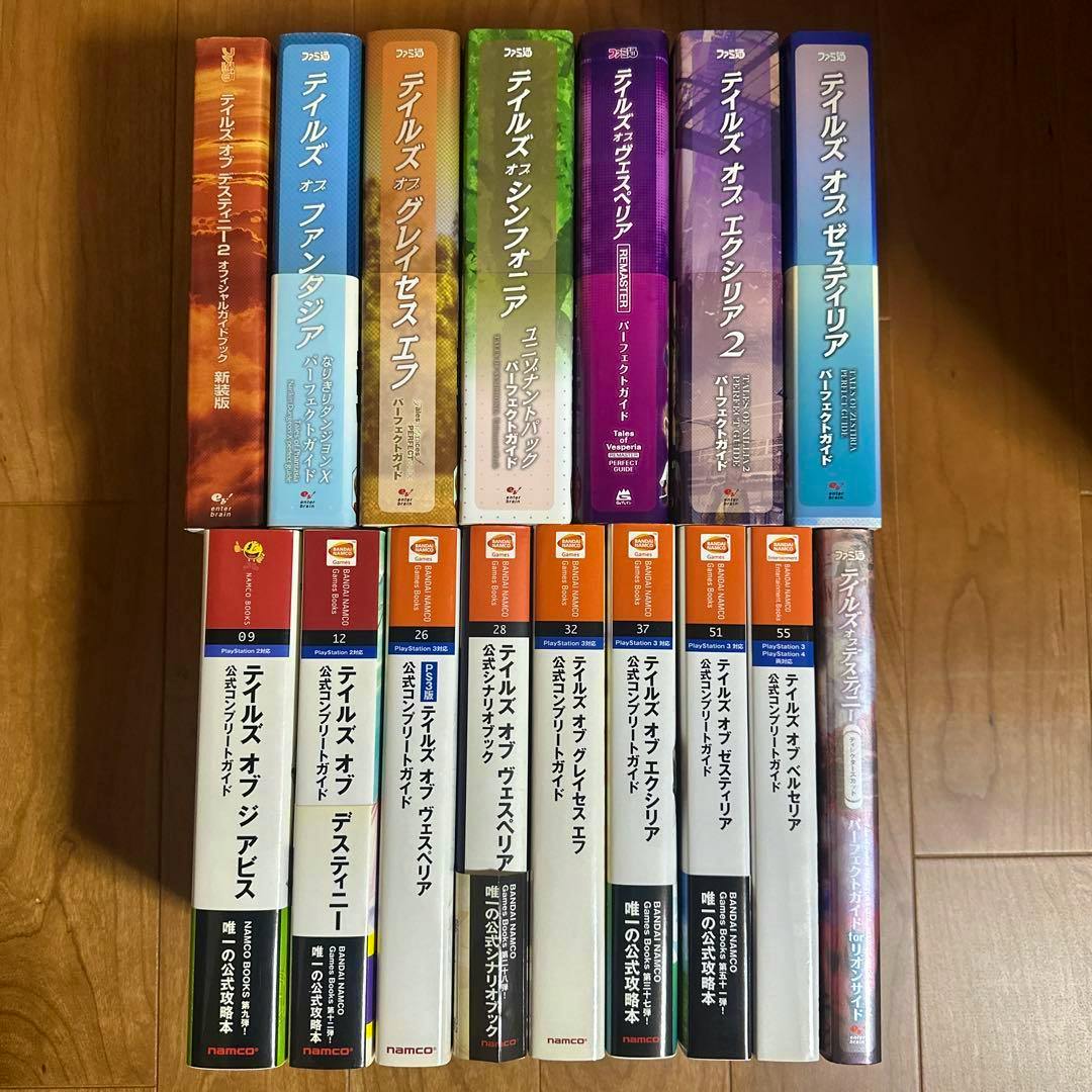 Spines of sixteen Japanese "Tales of" series strategy guide books arranged on a wooden floor.