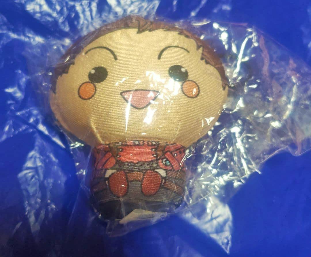 Front view of the Lloyd mochidaruma plush toy (Tales of Symphonia) in a clear plastic bag on a blue background.