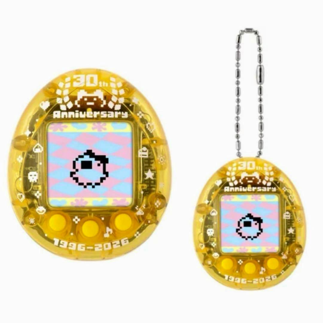 Yellow transparent Tamagotchi nano 30th anniversary toy shown twice on a white background, one larger and one with its chain.