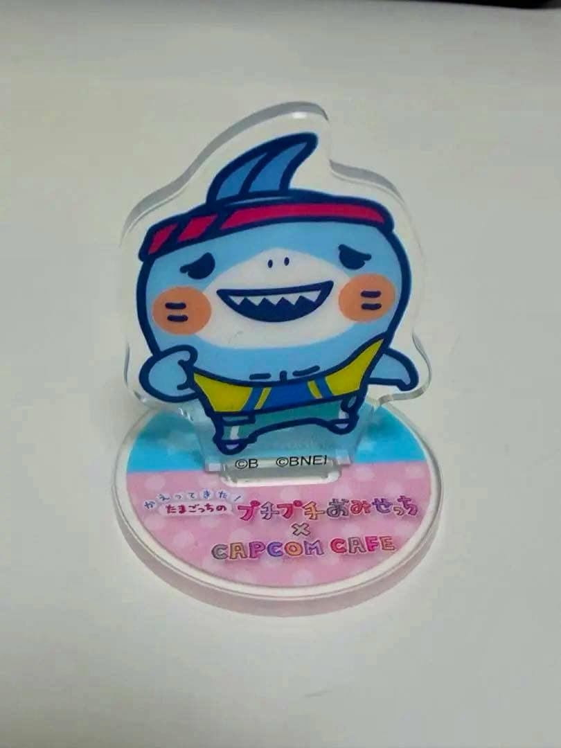 Assembled acrylic stand of たまごっち シャイクっち displayed on its round CAPCOM CAFE printed base.