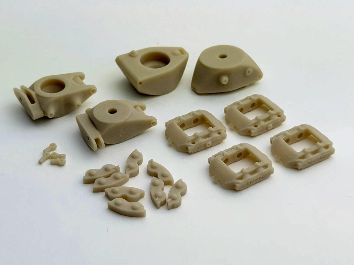 Several unpainted beige resin brake caliper and pad detail-up parts for the TAMIYA 1/12 Ferrari 641/2 displayed on a white background.