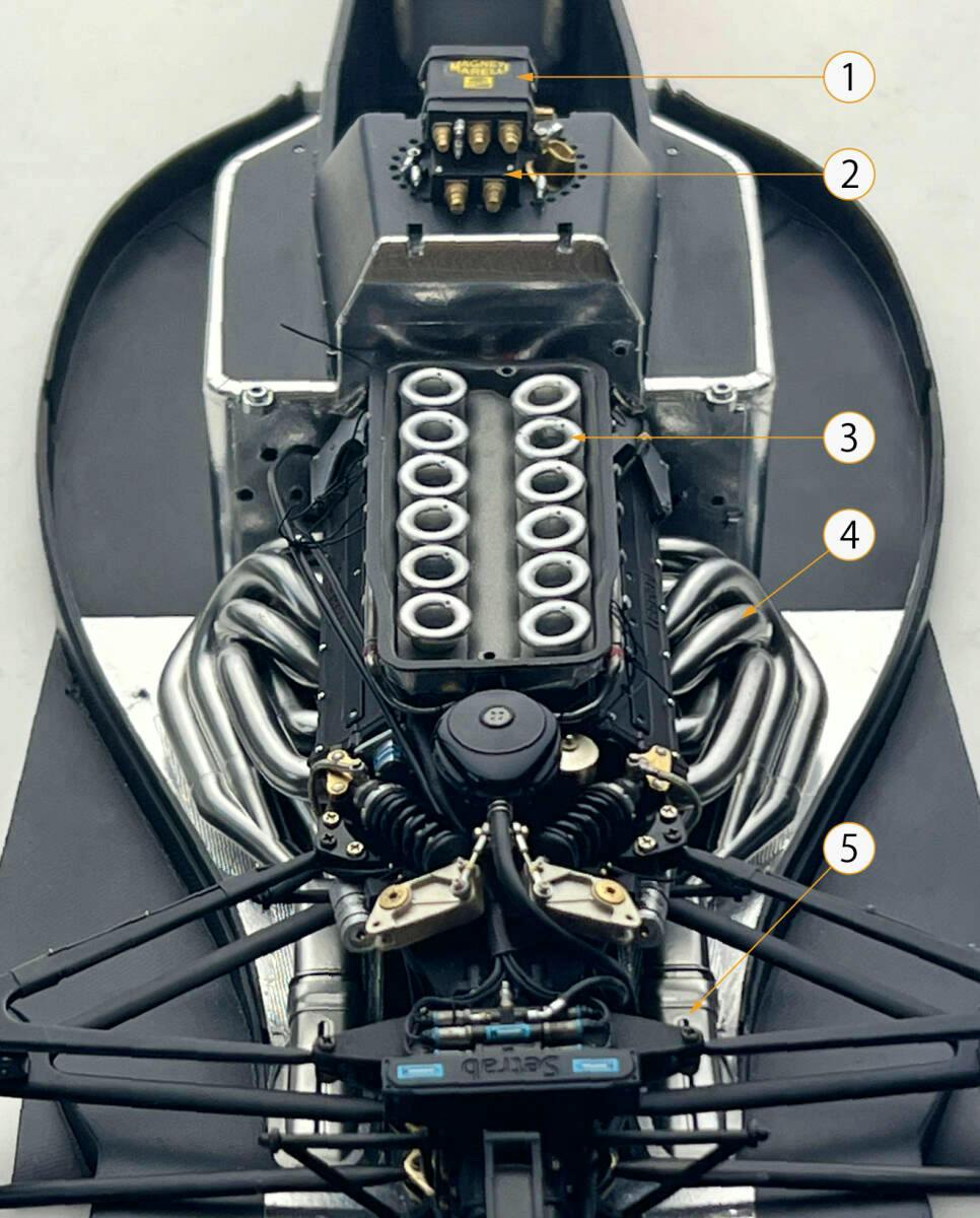 Close-up photo of a model Ferrari 641/2 engine bay showing installed exhaust pipes, air funnels, and an electrical box detail-up parts set.