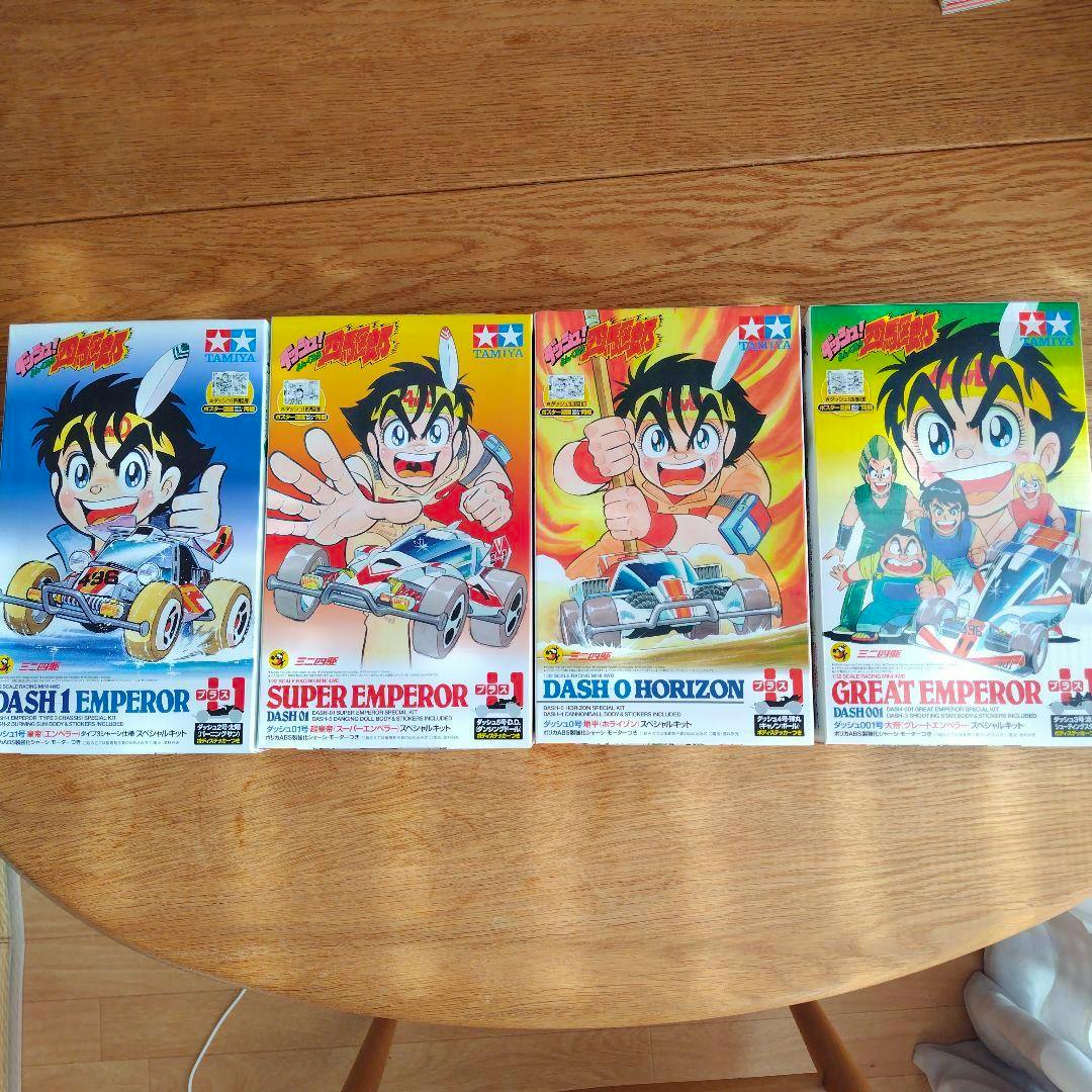 Four Tamiya Mini 4WD Dash Yonkuro special kit plastic model boxes arranged side-by-side on a wooden table, showing the front cover art for the four kits.
