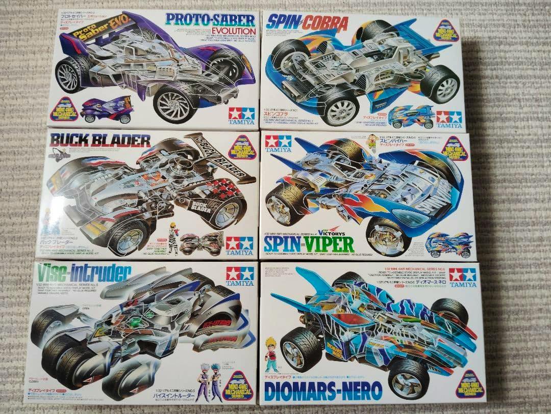 Photo of six Tamiya Mini 4WD model kit boxes showing box art for Proto-Saber Evolution, Spin Cobra, Buck Blader, Spin Viper, Vise Intruder, and Diomars-Nero.