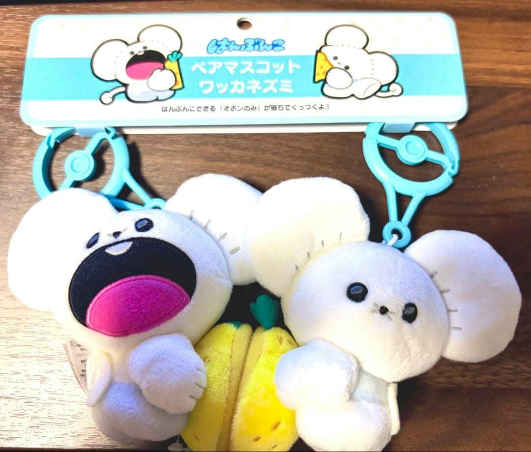 Two small white mouse plush keychain mascots attached to blue plastic clips with a cardboard header showing Japanese text, holding a yellow plush item.