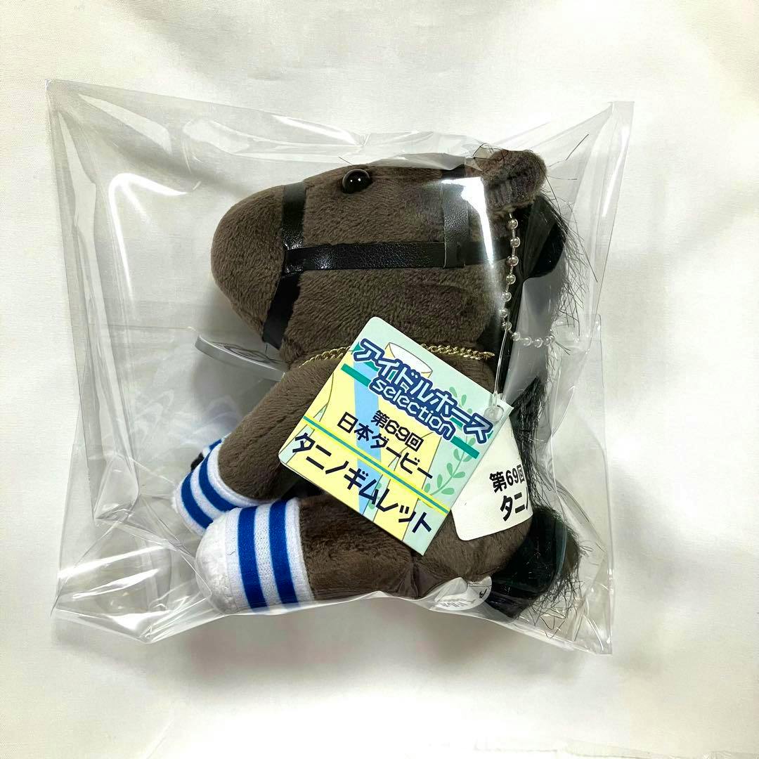 Brown horse plush keychain in clear plastic packaging with an attached paper tag visible.