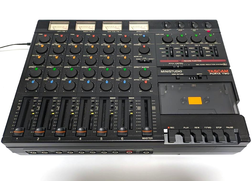 Top view of a TASCAM PORTA TWO cassette multitrack recorder showing faders, knobs, VU meters, and the cassette compartment.