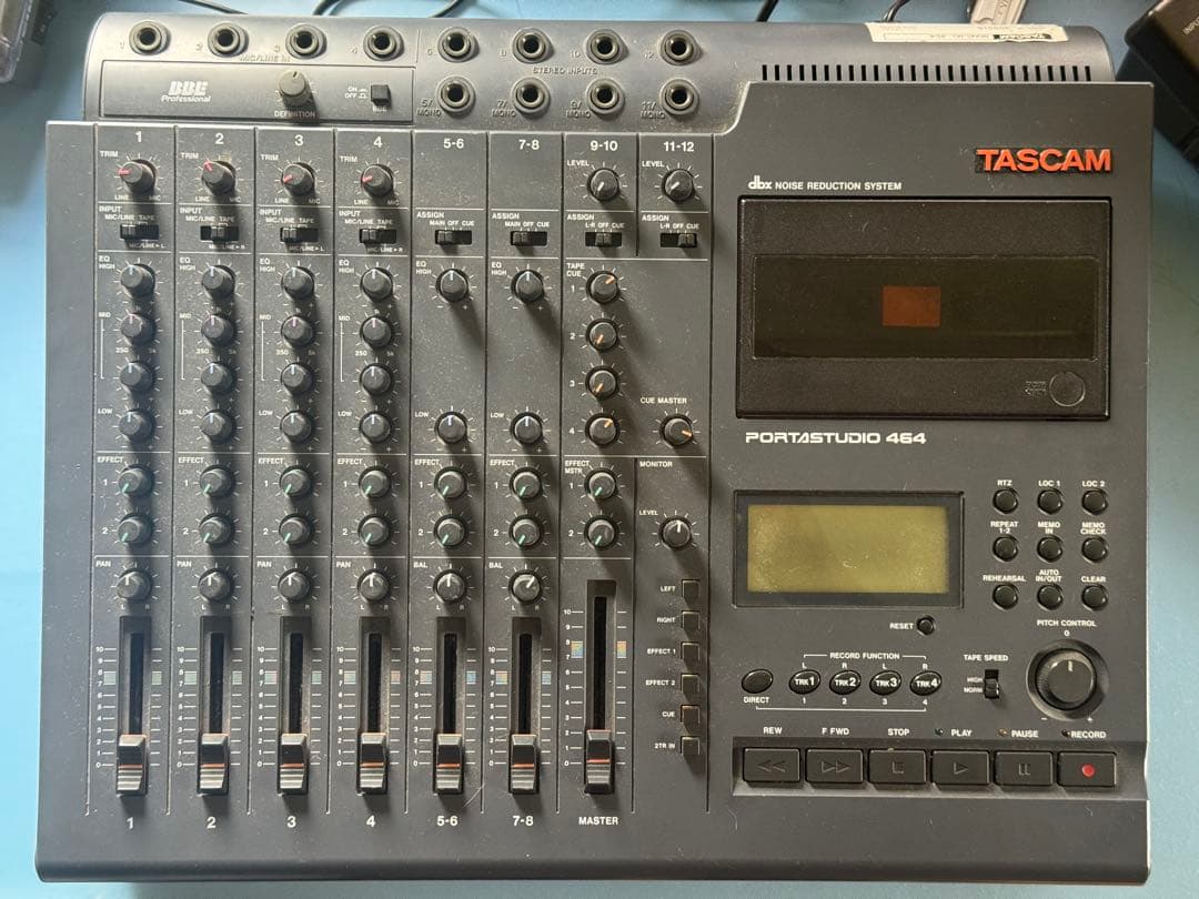 Top-down photo of the TASCAM Portastudio 464 multitrack recorder showing mixer channels with knobs and faders, the cassette transport window, and control buttons.