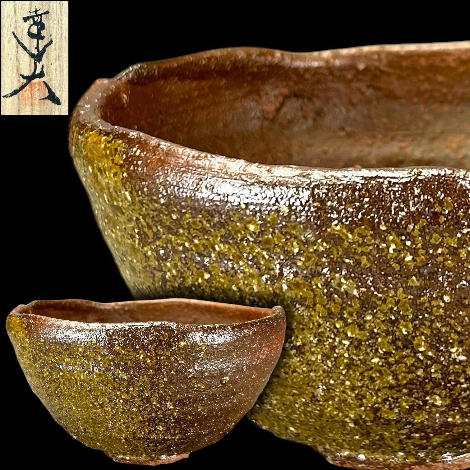 Close-up of the Bizen tea bowl showing brown‑green speckled glaze and textured surface with a wooden box signature inset.