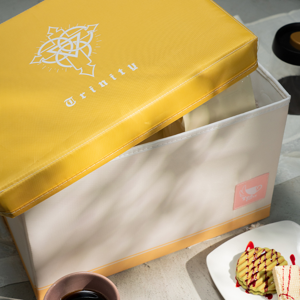 Photograph of the storage case (tea party) with a yellow lid partially removed, shown next to a cup and plate of desserts.