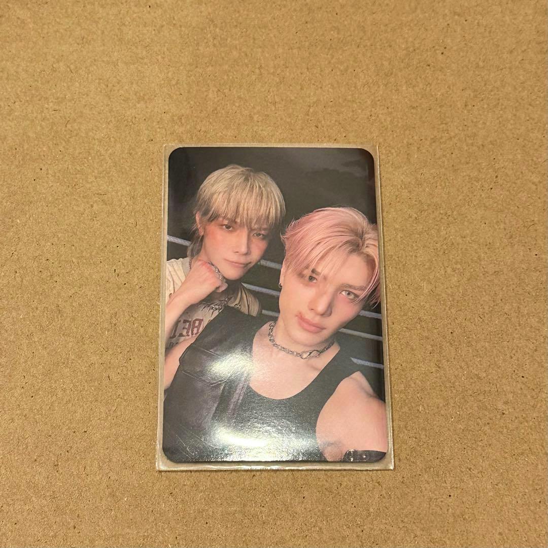 Photocard showing two people posing together in a plastic sleeve on a brown surface.