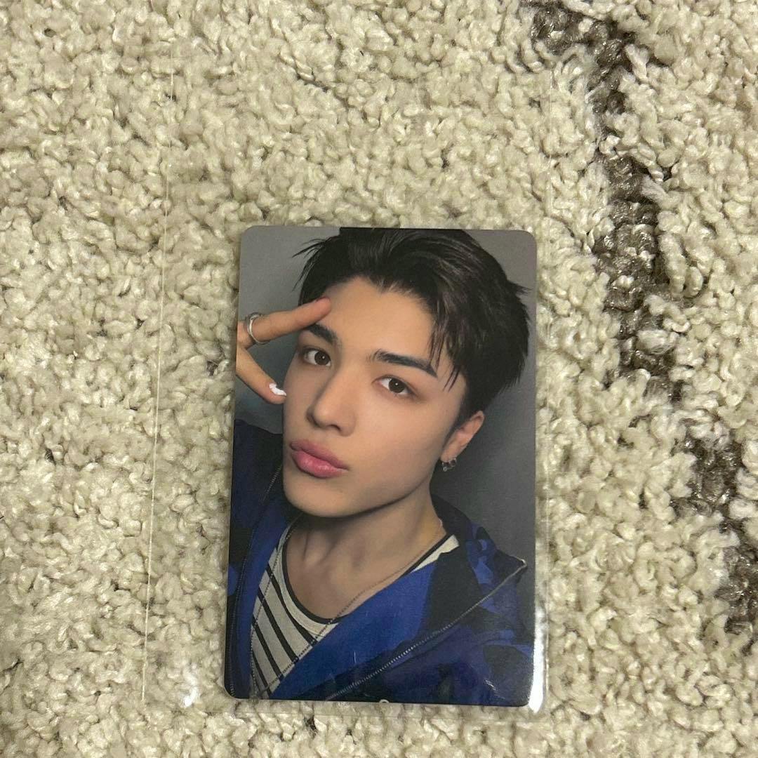A photocard featuring a portrait of a person placed on a beige carpet.