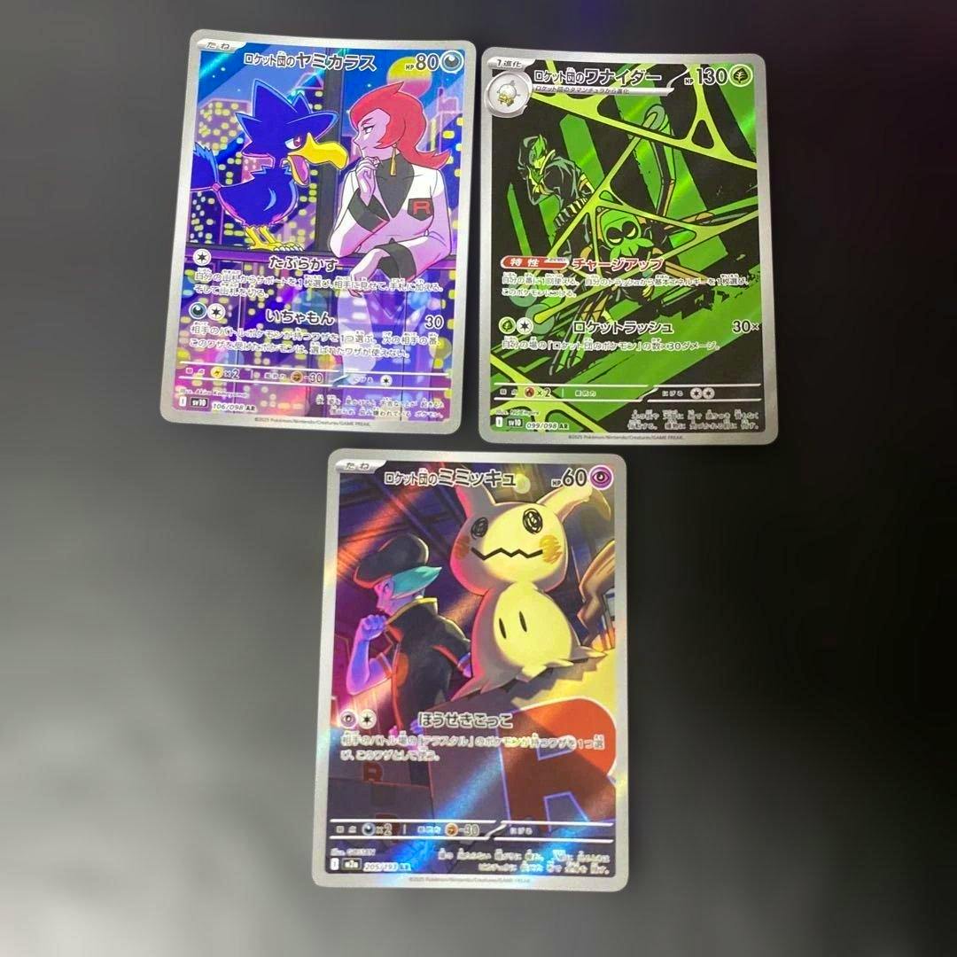 Three Pokémon trading cards (ロケット団のヤミカラス, ロケット団のワナイダー, ロケット団のミミッキュ) laid out on a dark surface.