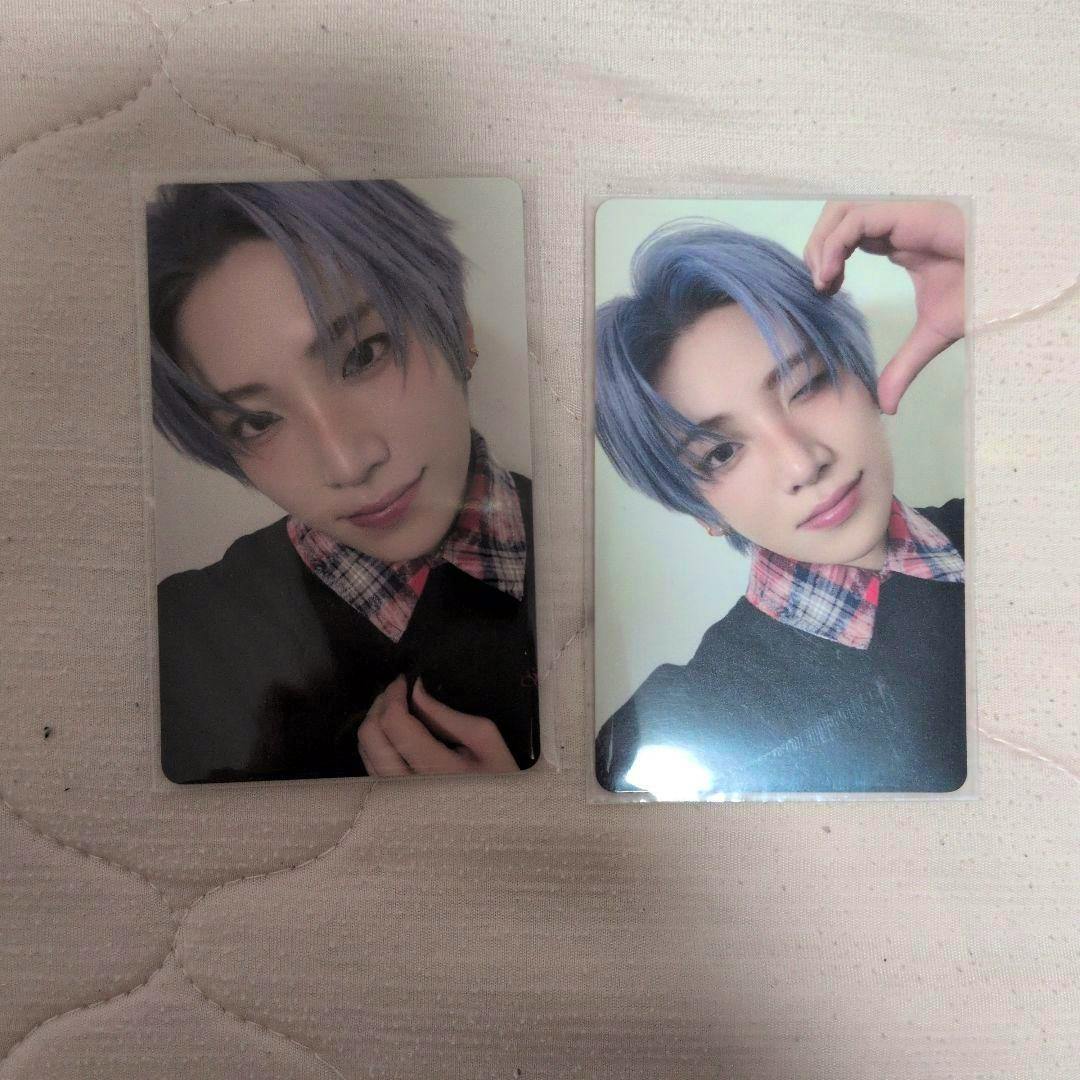 Two &TEAM photocards showing a blue-haired person in two poses placed side-by-side on a light quilted surface.
