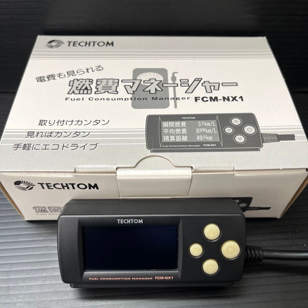 Techtom FCM-NX1 portable fuel consumption manager device pictured in front of its original box.