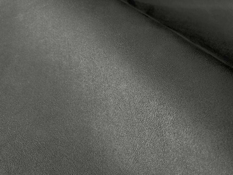 Close-up of matte black–dark gray artificial leather (polyester) fabric showing textured surface and a fold.