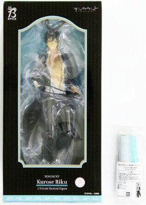 Boxed Kurose Riku figure visible through the windowed packaging with a rolled mini tapestry beside it.