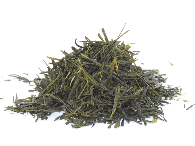 A pile of loose green tea leaves on a white background.