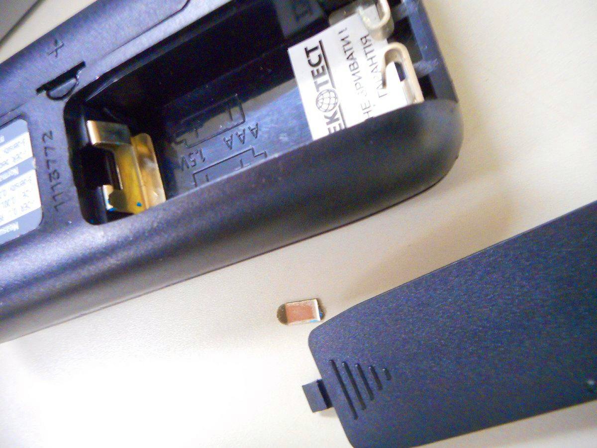 Close-up of the digital multimeter (no battery) showing its open battery compartment and removed cover.