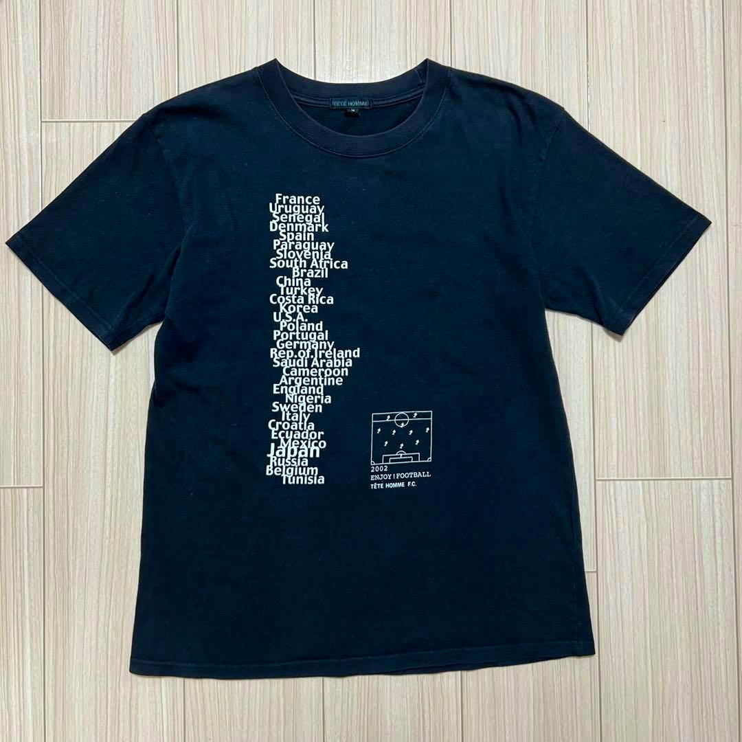Black TETE HOMME men's cotton T-shirt laid flat showing a vertical white list of country names and a small football pitch graphic.