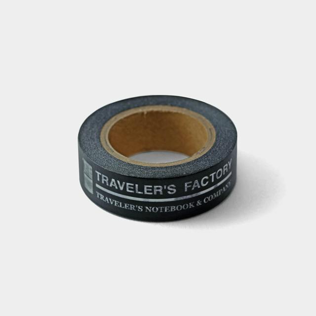 A black masking tape roll printed with "TRAVELER'S FACTORY" on the side.
