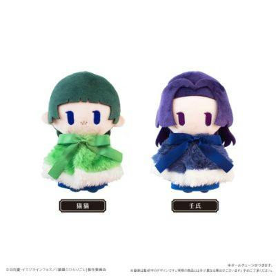 Two cape-wearing plush toys, one with green hair and green cape and one with purple hair and blue cape, on a white background.