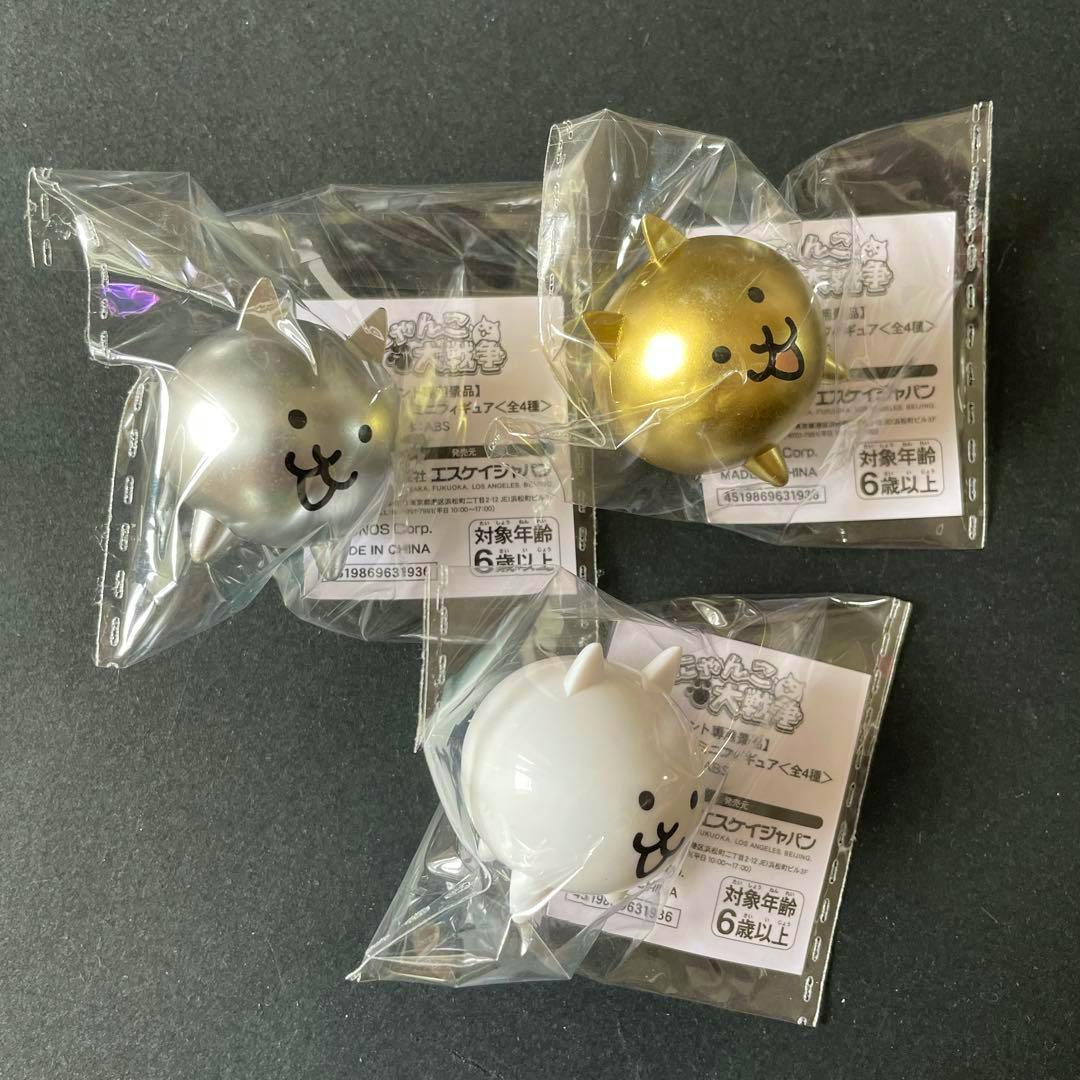 Three sealed mini cat mascot plastic figures (set of three) shown on a dark background.