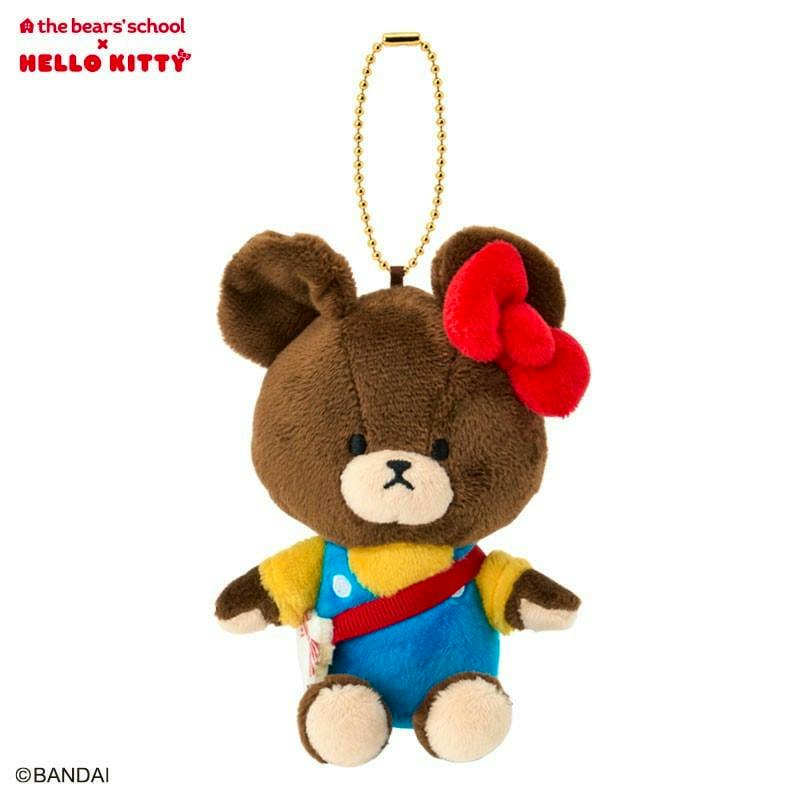 Front view of the Jackie mascot plush keychain — a brown bear with a red bow, yellow shirt, and blue overalls on a white background.