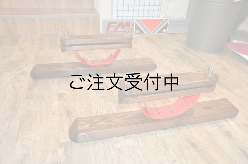 Three wooden stands with red curved metal supports arranged on a wooden floor.