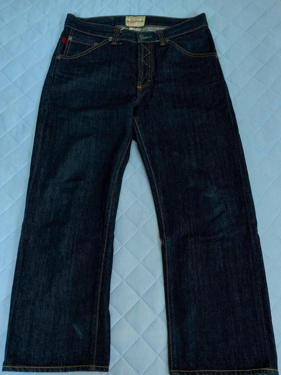 Flat-lay front view of The Flat Head men's dark denim jeans laid flat on a quilted surface.