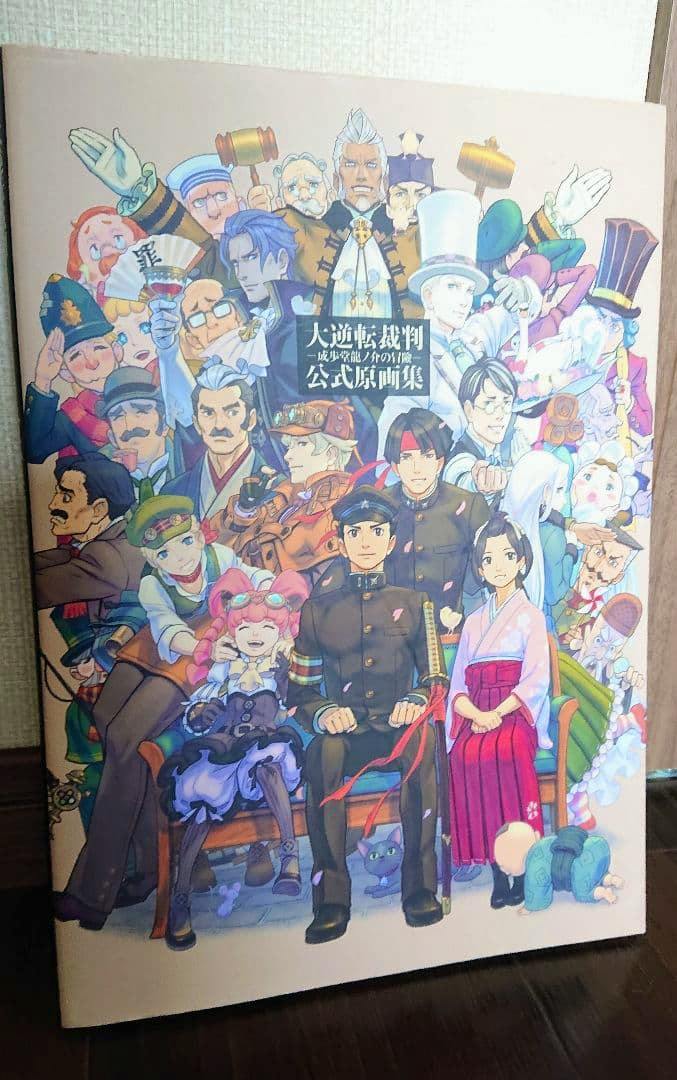 Front cover of the illustration book showing the group character artwork and the Japanese title of 大逆転裁判 成歩堂龍ノ介の冒險 公式原画集.