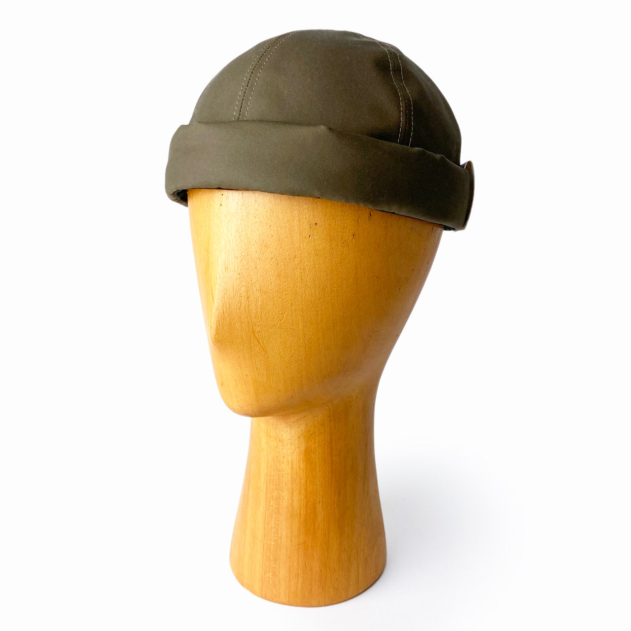 A roll cap displayed on a wooden mannequin head against a white background.