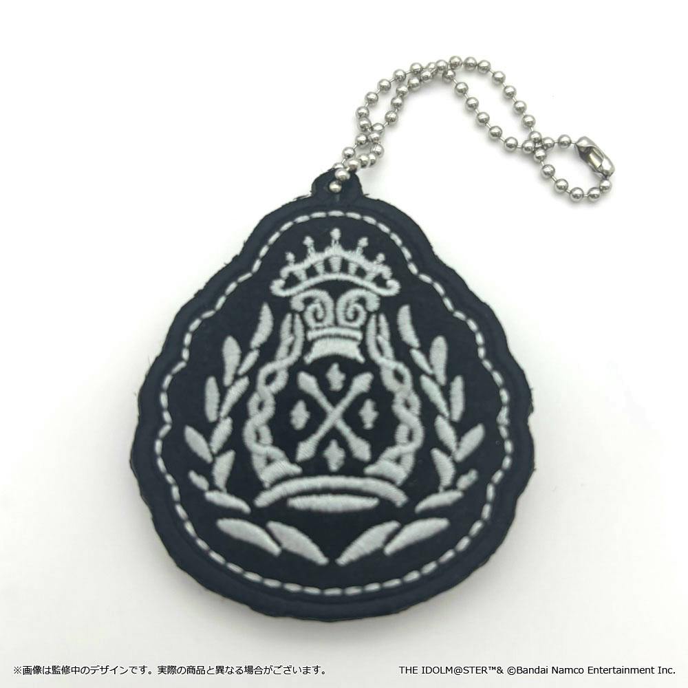 A blue fabric keychain patch with a white embroidered crest design and a silver ball chain on a white background.