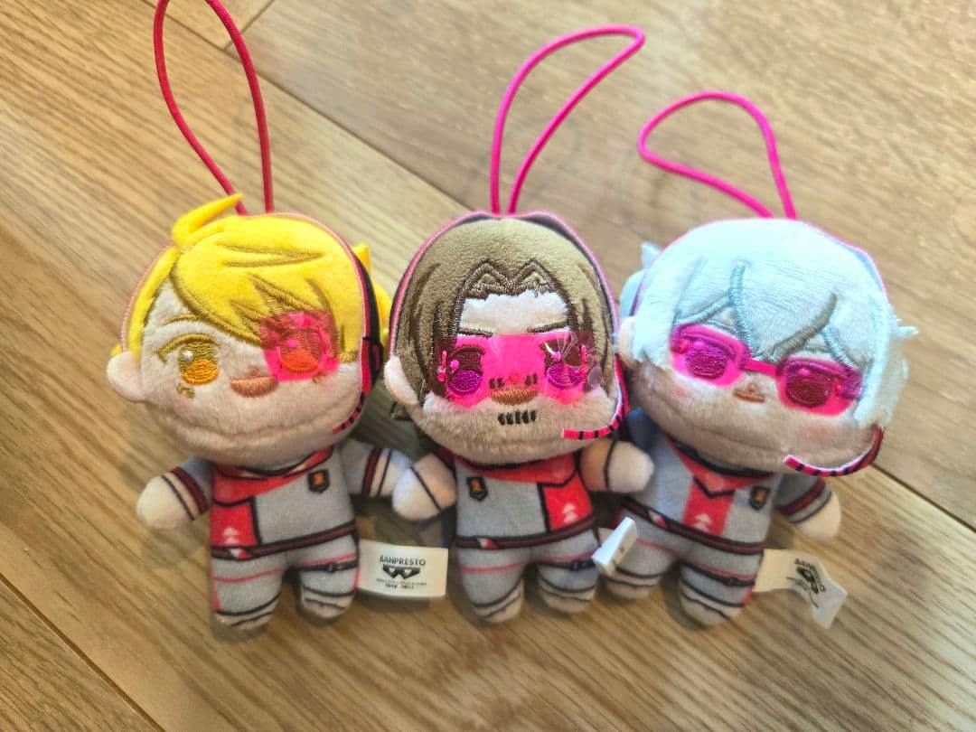 Front view of three SideM S.E.M plush keychain dolls arranged side by side on a wooden floor.