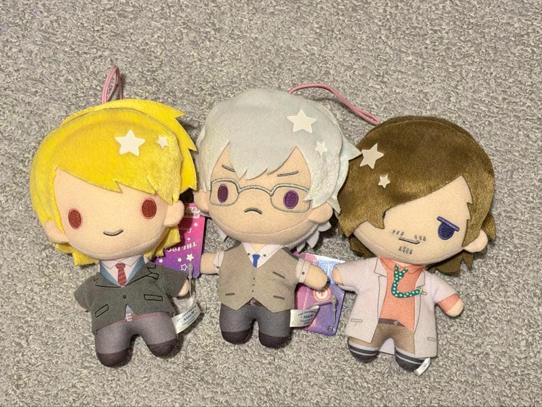 Three Idolmaster SideM S.E.M Sanrio collaboration plush toys lying on a carpeted surface.