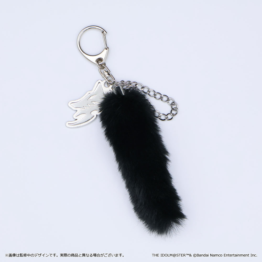 Photo of a black furry tail keychain with a silver chain and metal logo charm on a white background.