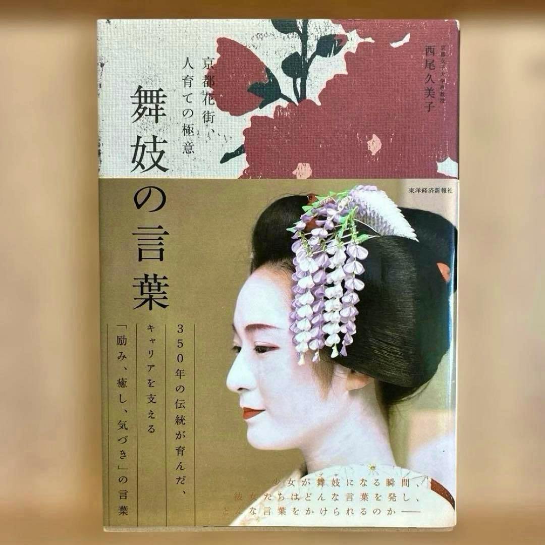 Front cover of the book showing a profile portrait of a maiko with a floral hair ornament and the Japanese title text.