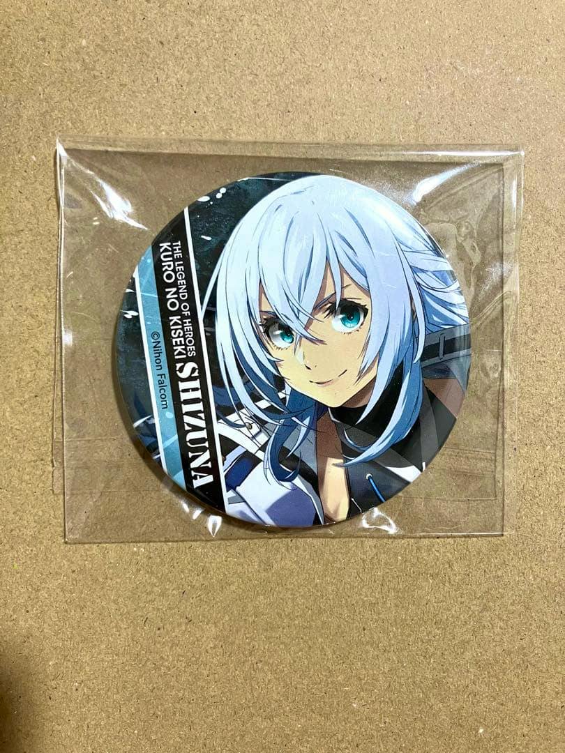 Front view of the Shizuna can badge (英雄伝説 黎の軌跡) showing the character illustration inside a clear plastic sleeve on a brown background.