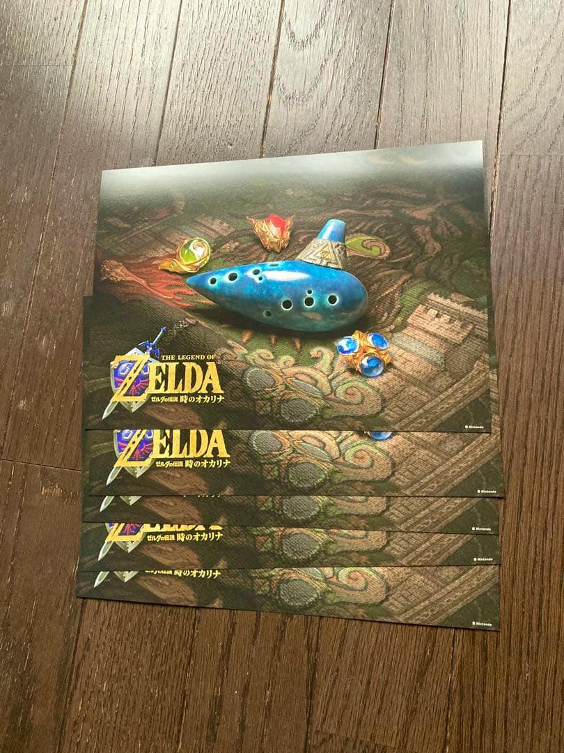 Five ゼルダの伝説 時のオカリナ (The Legend of Zelda: Ocarina of Time) Bic Camera limited flyers stacked on a wooden floor showing an ocarina and the Zelda logo.