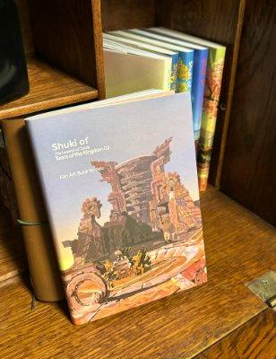 Front cover of the Shuki of Tears of the Kingdom 02 : ハイラル語 illustration book placed upright on a wooden shelf with other books behind it.