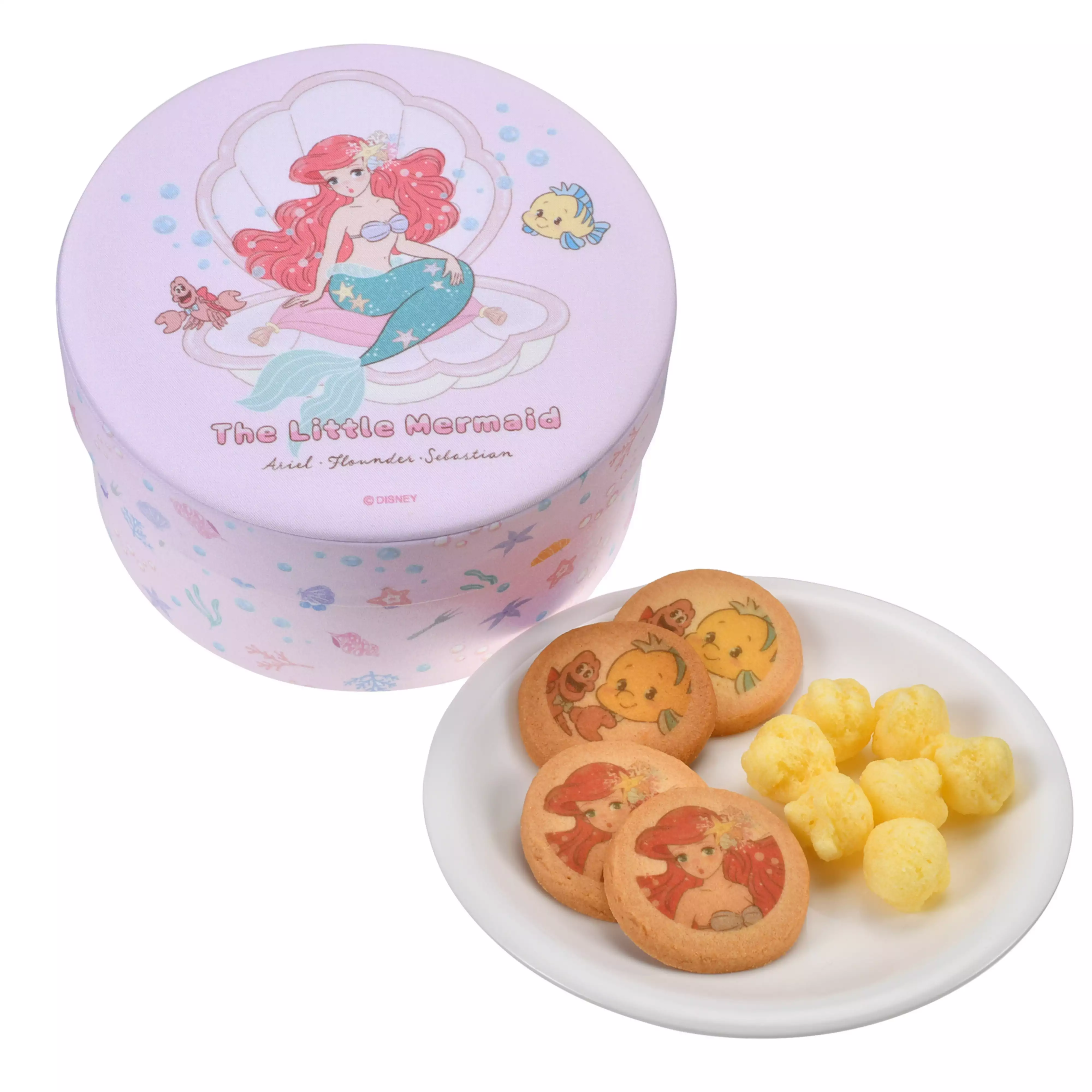 A round illustrated Little Mermaid tin box next to a plate of cookies printed with characters and yellow corn snack puffs.
