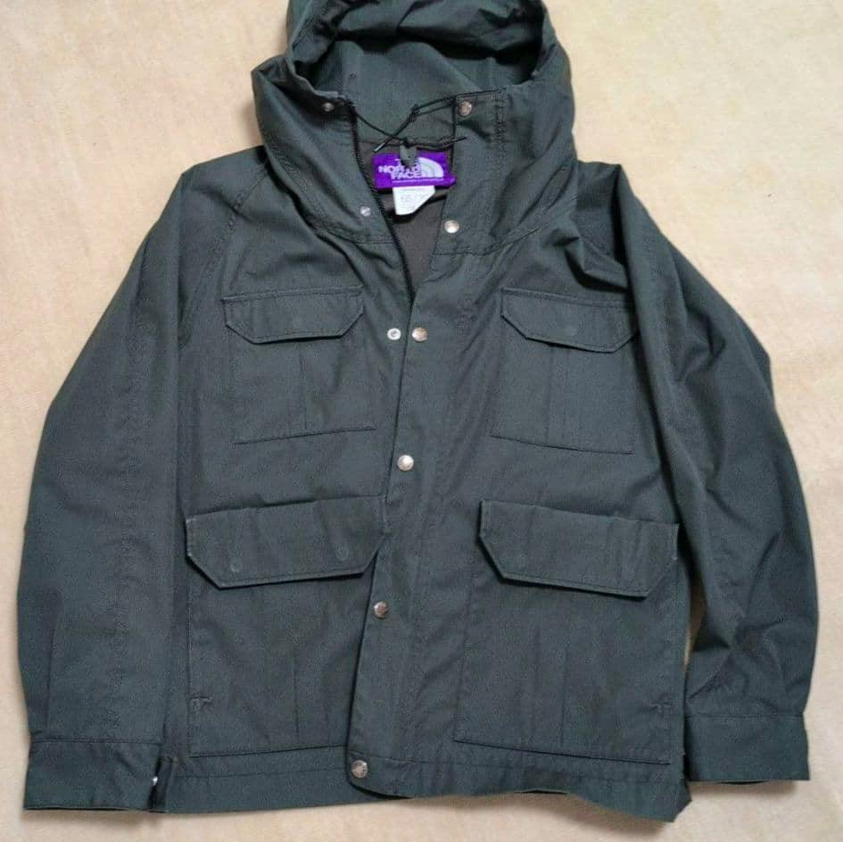 Gray The North Face Purple Label men's mountain parka laid flat showing the front, hood, and multiple flap pockets.