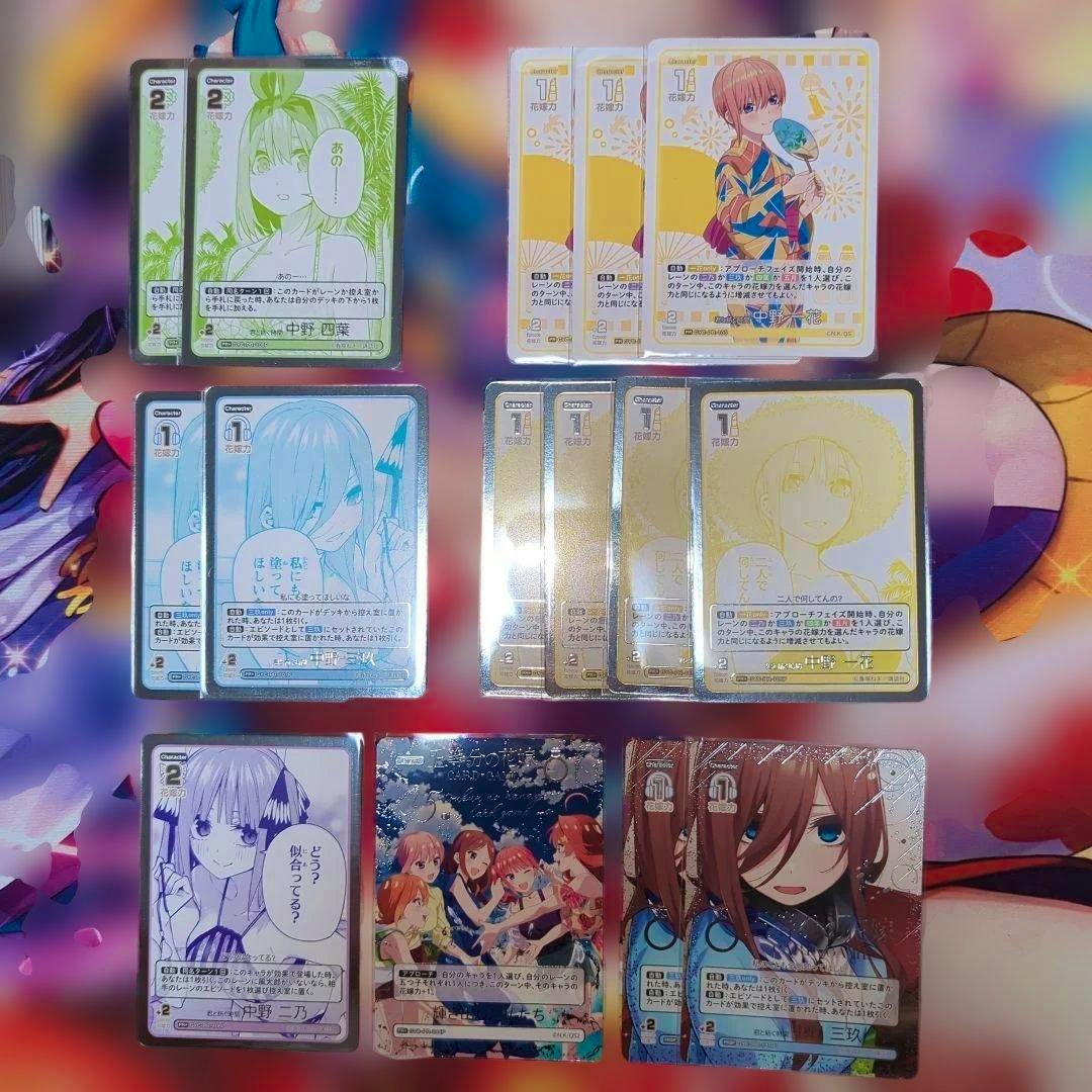 Photograph of multiple trading cards from 五等分の花嫁 arranged on a colorful background showing various character illustrations.