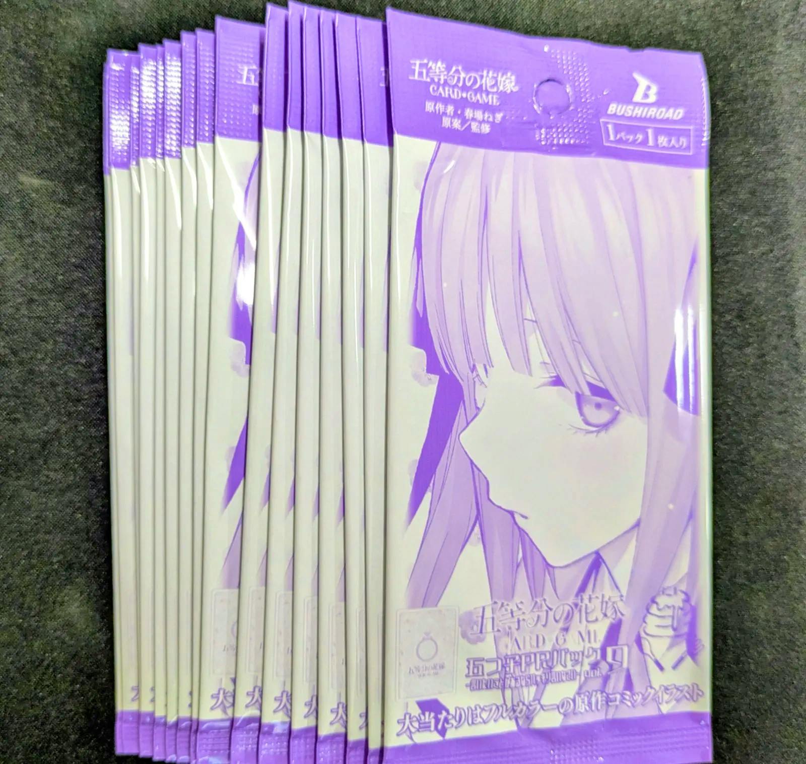 Several sealed purple-themed trading card PR packs for 五等分の花嫁 (The Quintessential Quintuplets) arranged on a dark surface.
