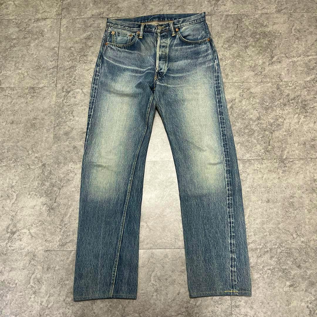 Front view of men's jeans laid flat on a tiled floor.
