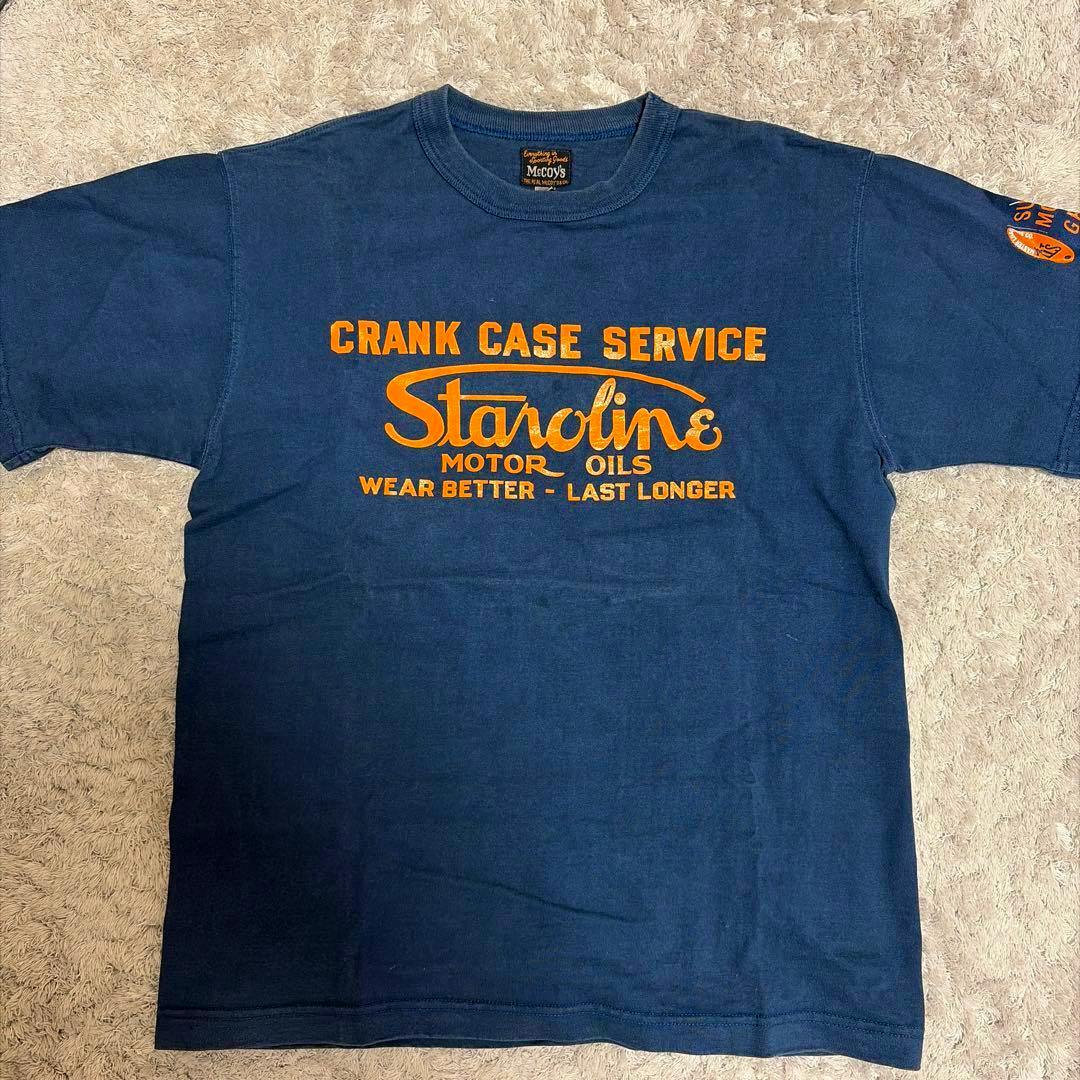 Navy men's cotton T-shirt laid flat showing an orange "Crank Case Service Staroline Motor Oils" graphic on the front.